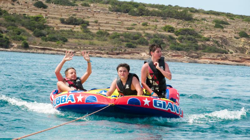Tres chicos siendo remolcados en un hinchable en el mar en el curso de idiomas en malta