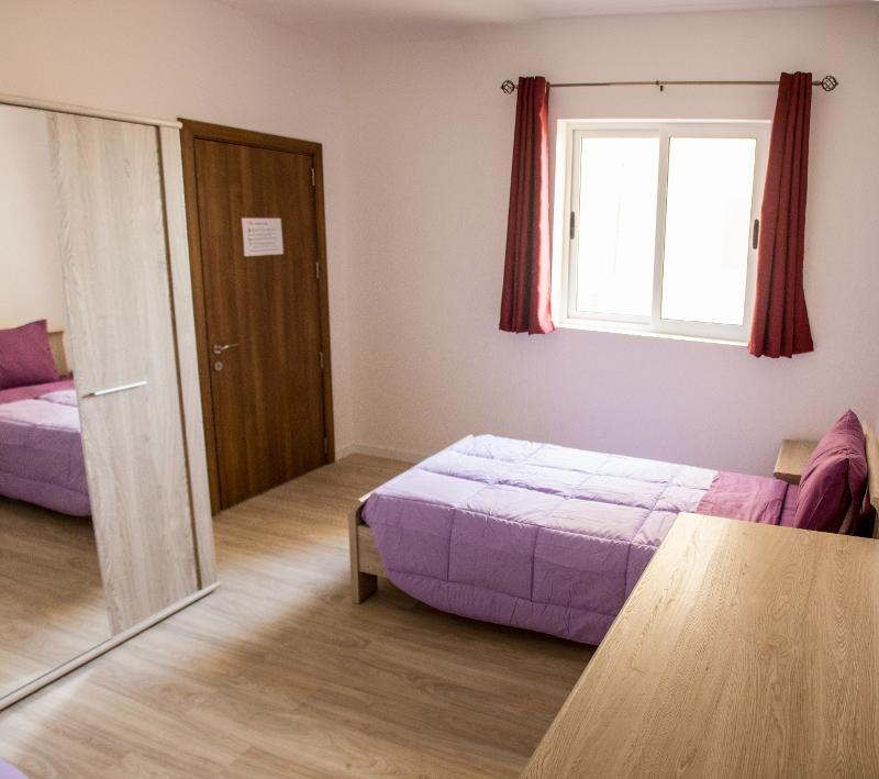 Habitación individual con escritorio y armario con espejo en el curso de idiomas en malta