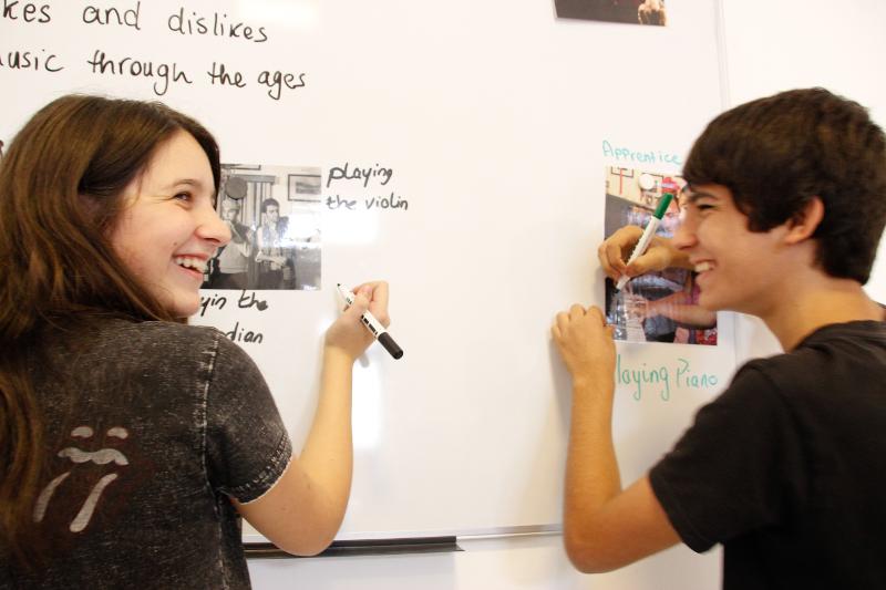 Chico y chica en clase de inglés escribiendo en la pizarra en el curso de idiomas en malta