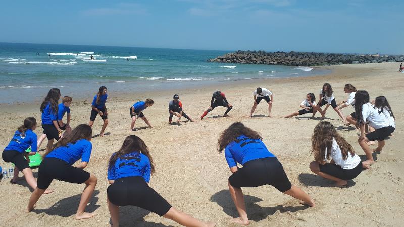 Niños calentando antes de realizar surf en un curso frances francia