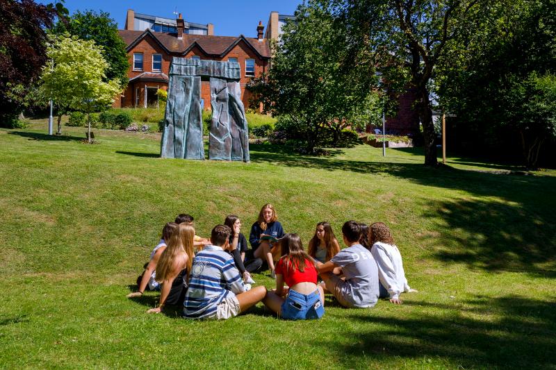 Niños sentados en la hierba durante un curso de idiomas en inglaterra