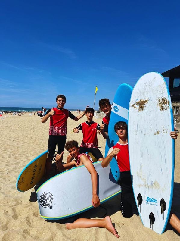 foto de unos niños en la playa con tablas de surf mientras participan en un viaje idiomas verano