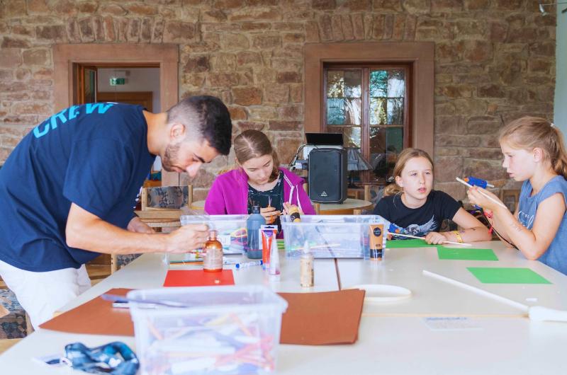 Foto de unos niños realizando manualidades durante un campamento de verano en Alemania para niños