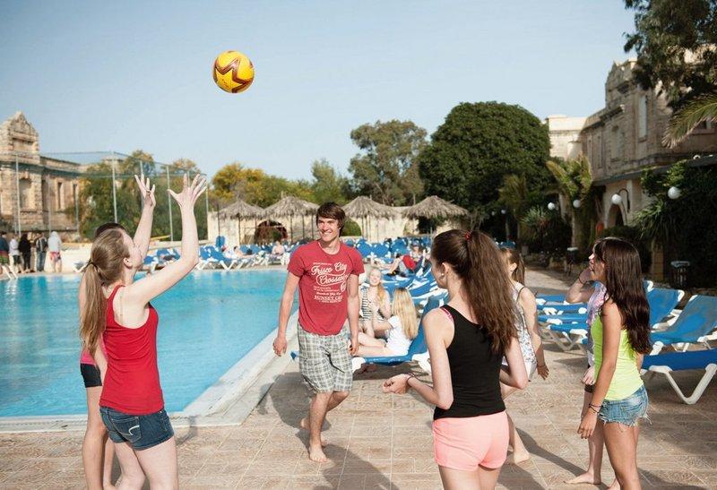 Jóvenes jugando con un balón al lado de la piscina en el curso de idiomas en malta
