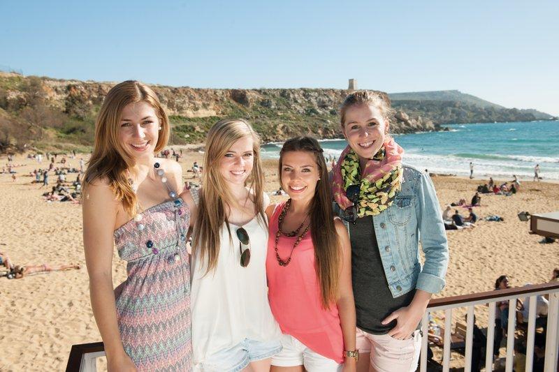 Chicas posando enfrente de la playa en el campamento de verano en Malta