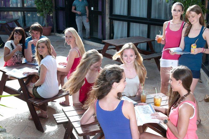 Jóvenes con bebidas sentadas en mesas exteriores en el curso de Idiomas juvigo en malta 