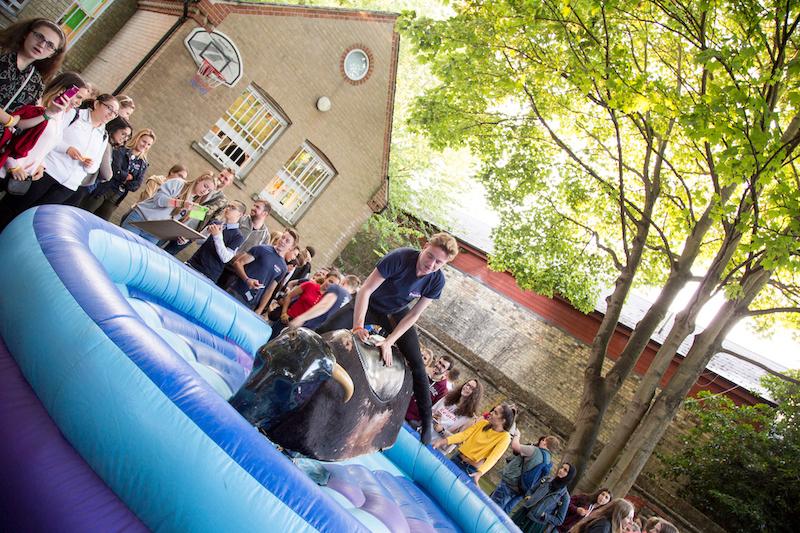 Niño subido al toro mecánico rodeado de participantes en los cursos de ingles en cambridge