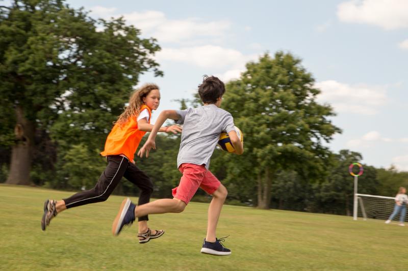 Jóvenes corriendo con el balón en la mano en los juegos al aire libre del curso de idiomas inglaterra 