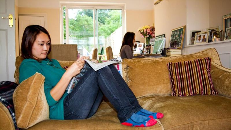 Chica del curso de ingles en inglaterra sentada en el sofá de la casa de acogida 