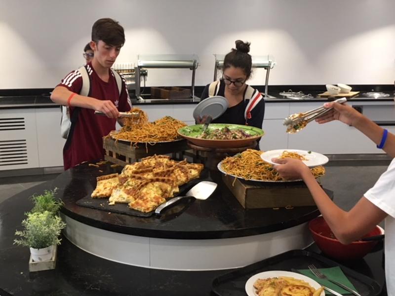Tres estudiantes cogiendo comida del buffet en el curso de idiomas en inglaterra 