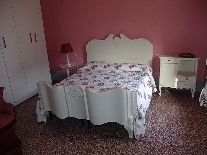 Dormitorio de la familia de acogida con cama de matrimonio totalmente equipado y decorado en color rosa del curso de idiomas en italia 