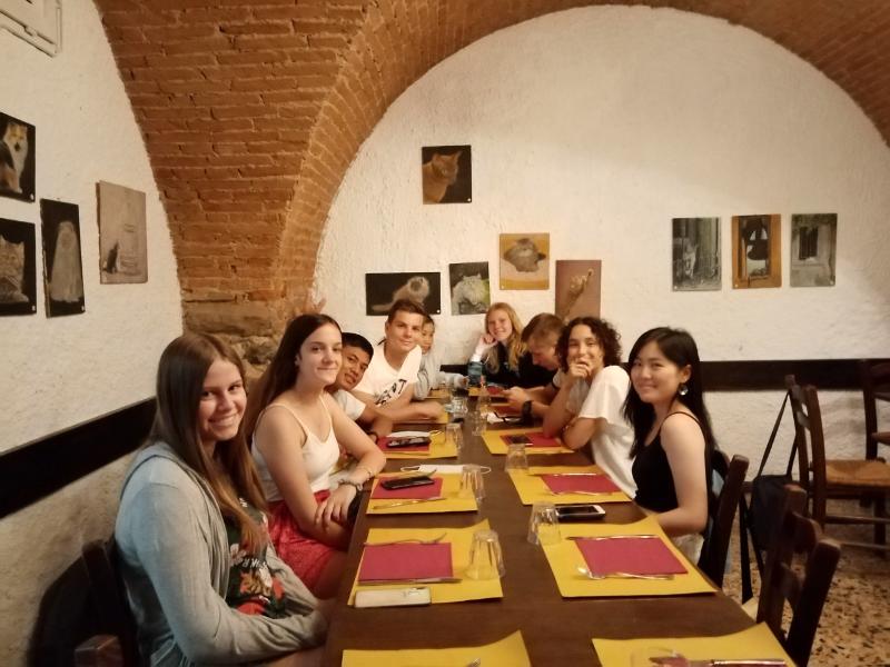 Grupo de participantes del curso de italiano en italia sentados en la mesa de un restaurante típico italiano