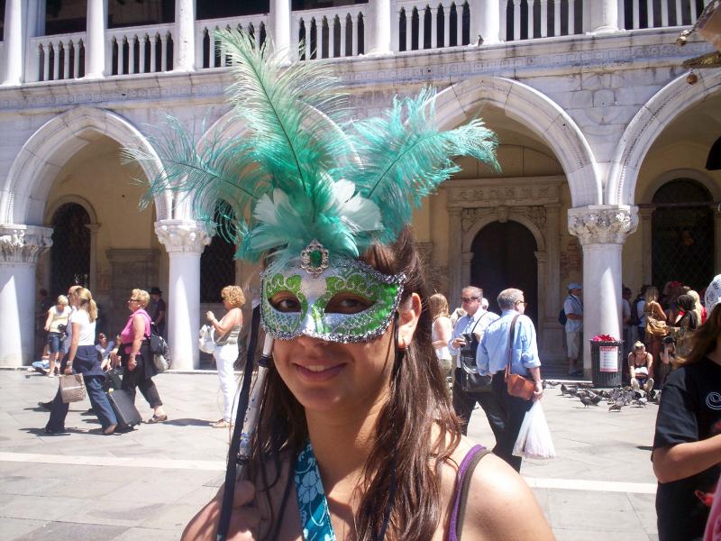 Joven con una máscara veneciana verde con plumas en el curso de idiomas en italia 