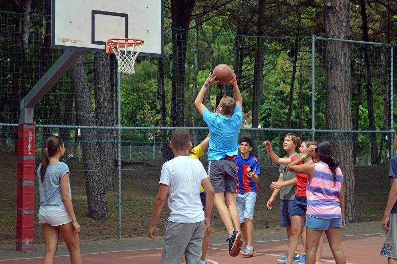 Grupo de participantes del curso de idiomas en italia jugando a un partido de baloncesto 