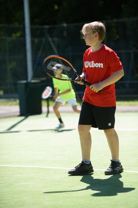 Niño con la raqueta de tenis jugando un partido en el curso ingles escocia 