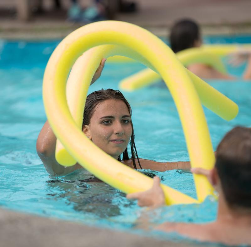 Joven en la piscina con un churro amarillo en el curso de ingles escocia 