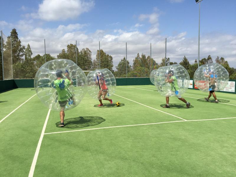 Grupo de niños jugando al fútbol burbuja durante un campamento de verano en cadiz para niños