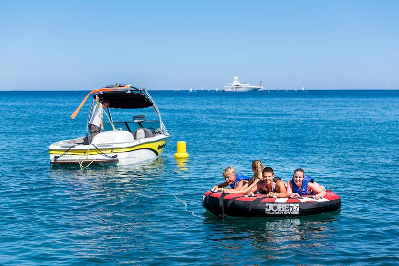 Niños riéndose en un banana boat junto a un barco en el curso de frances en francia