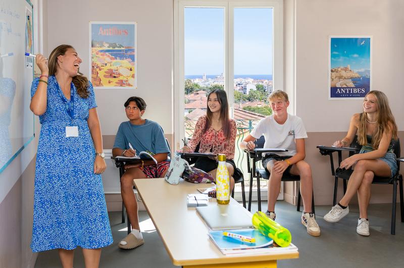 Estudiantes y profesora riéndose en clase en el curso de idiomas en francia