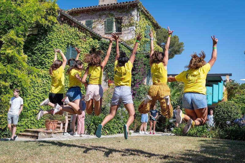 Grupo de jóvenes con camisetas amarillas del curso de idiomas en francia saltando de espaldas 