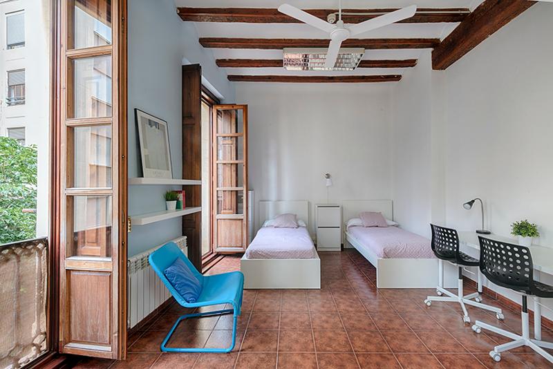 Habitación doble con escritorio, sillas y sillón en el curso de español en españa