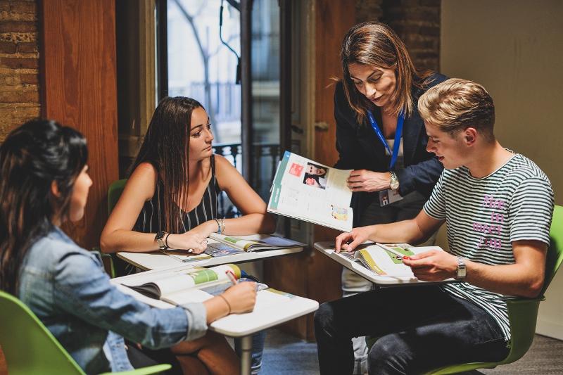Jóvenes atendiendo en clase a su profesora en el curso de español en españa