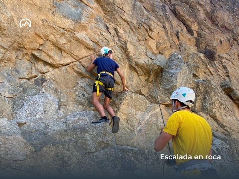 Niño haciendo escalada en roca en el campamento de verano