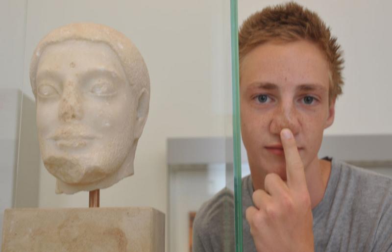 Chico posando con un busto sin nariz en un museo de cultura en campamento de verano alemania