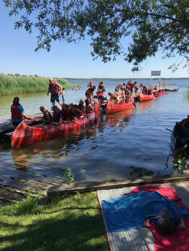 Campers montando en canoa en un lago rodeado de naturaleza bajo el sol en un campamento alemania verano  