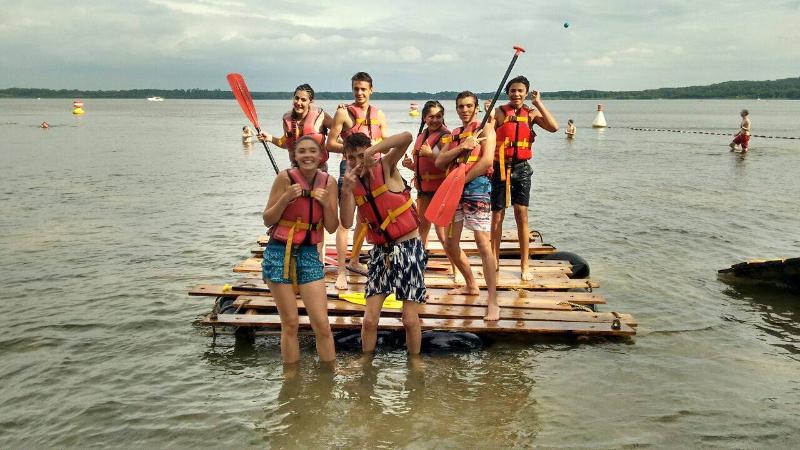 Grupo de campers posando con chalecos salvavidas en el agua con remos bañándose en campamento en aleman