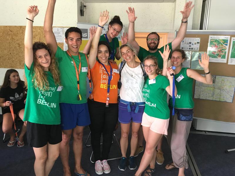 Grupo de monitores levantan las manos contentos para dar la bienvenida en campamento de verano en alemania