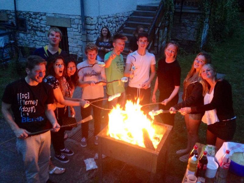 Jóvenes en una hoguera cocinan nubes de azúcar en velada nocturna barbacoa en campamento de verano en alemania
