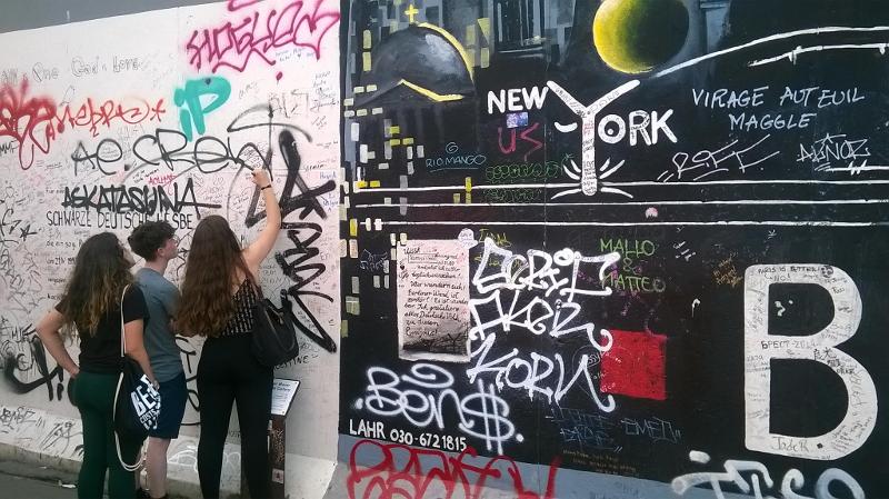 Jóvenes pintan su firma en el muro de berlin westend en curso de aleman en alemania