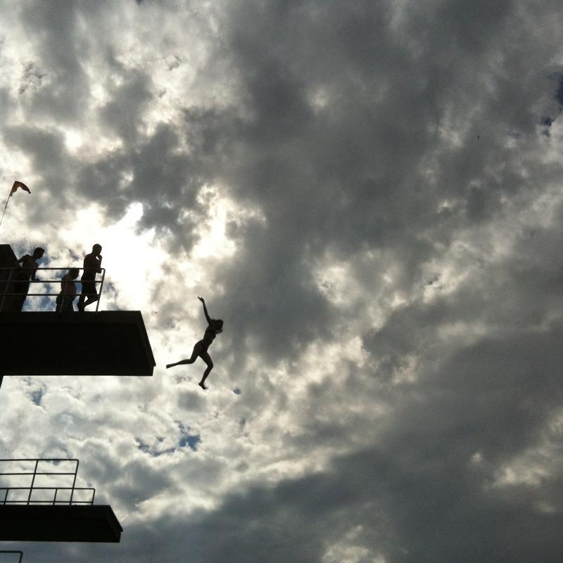 chica saltando desde un trampolín al agua con el cielo de fondo en curso de verano en alemania