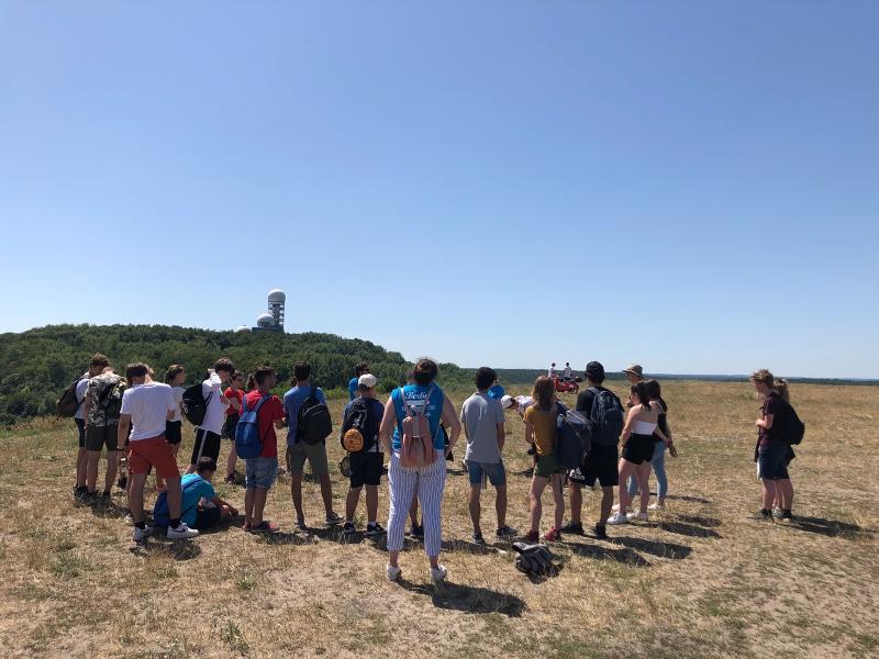 Grupo de jóvenes campistas atienden a una demostración en la montaña del campo sobre la naturaleza bajo el sol en curso de aleman en alemania verano