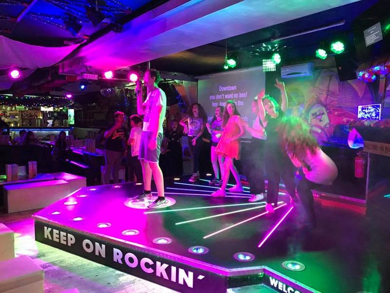 Jóvenes en el escenario de una discoteca con luces cantan karaoke y bailan en curso de aleman alemania
