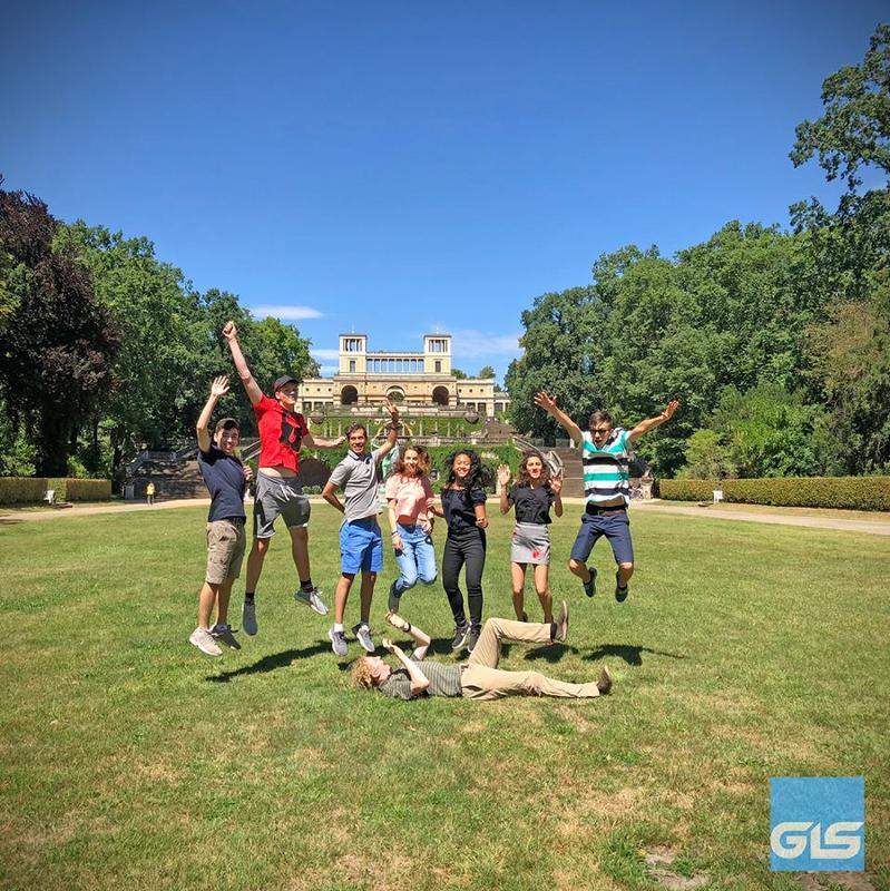 Jóvenes saltan y posan frente a un monumento en Potsdam en Brandemburgo en curso aleman alemania verano