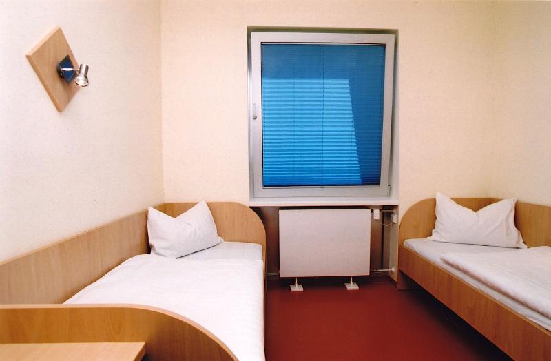 Habitación doble con dos camas individuales con cómoda y una ventana en el medio en curso aleman en alemania