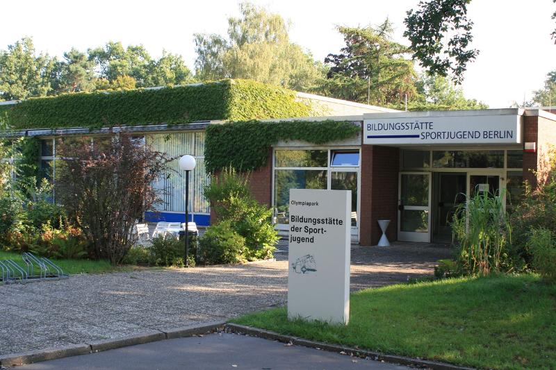 Escuela de idiomas rodeado de naturaleza con un cartel y una zona exterior con mesas y sillas en curso idiomas alemania