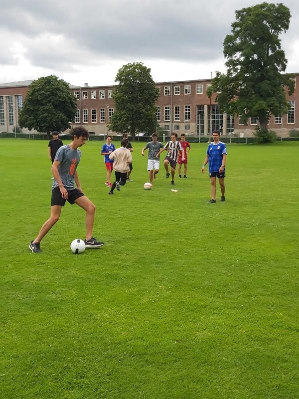 Jóvenes juegan un partido de fútbol en grupos en un campo de césped al lado de las instalaciones del curso de aleman en alemania verano