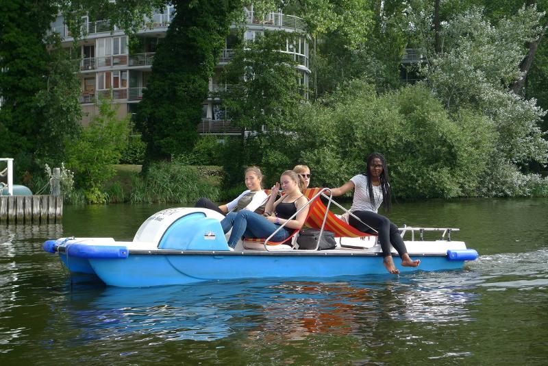 Cuatro jóvenes navegan en un barco a pedales por el río bajo el sol en curso aleman en alemania