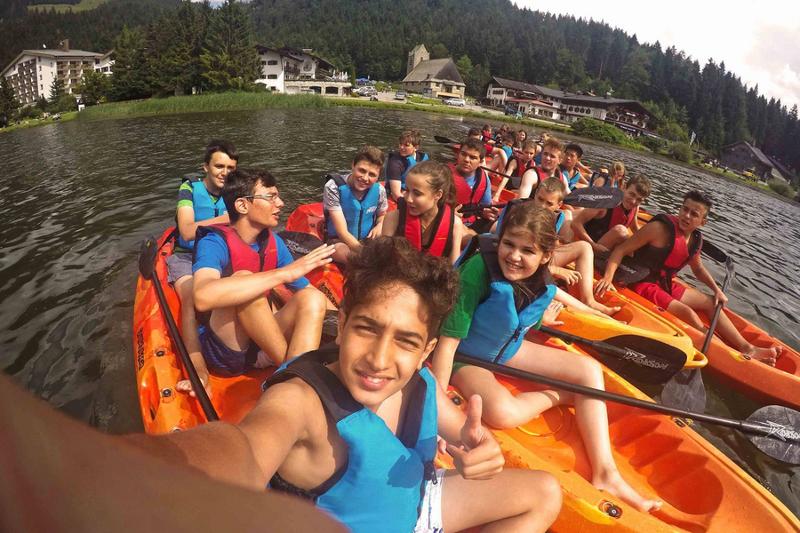 Grupo de campistas por agrupados en canoas sobre el agua mientras utilizan los remos para mantener las canoas juntas en curso verano alemania