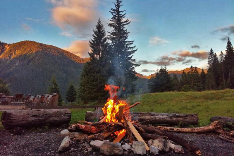 Hoguera encendida en el campo con árboles y una montaña de fondo mientras atardece en curso aleman alemania