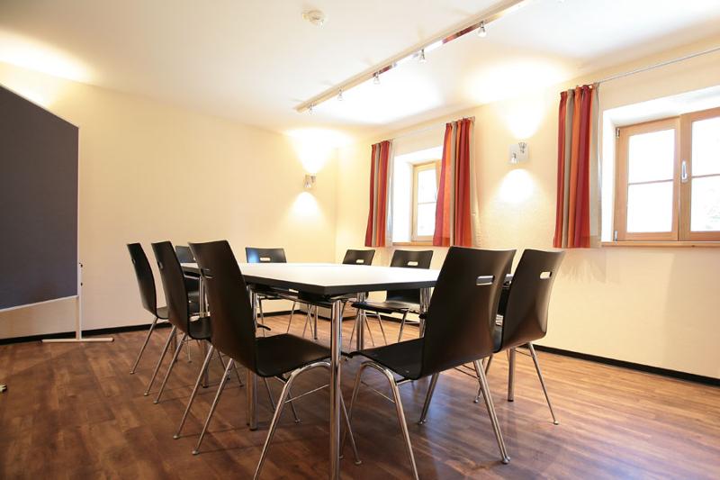 sala de reuniones con mesa, sillas y una pizarra frente a ventanas en curso de verano alemania