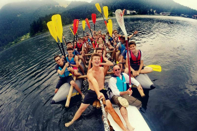 Grupo de campistas se hacen un selfie con los remos levantados en una barca hinchable en un lago en la montaña en curso aleman alemania