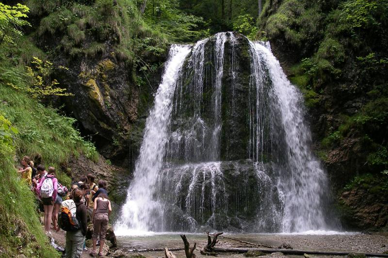 Campistas visitan una cascada en medio de una montaña rodeada de naturaleza en curso de aleman en alemania en verano