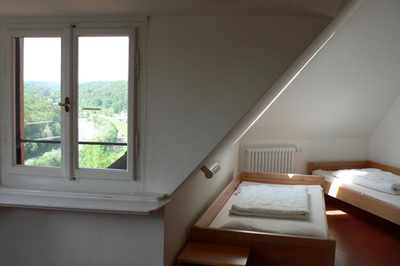 Habitación doble con techo inclinado con dos camas individuales y una ventana con vistas a la montaña en curso aleman alemania