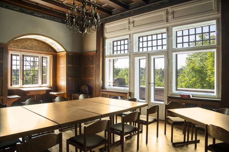 Comedor de madera con mesa y sillas en frente de una grande ventana con vistas a la naturaleza en curso de idiomas en alemania