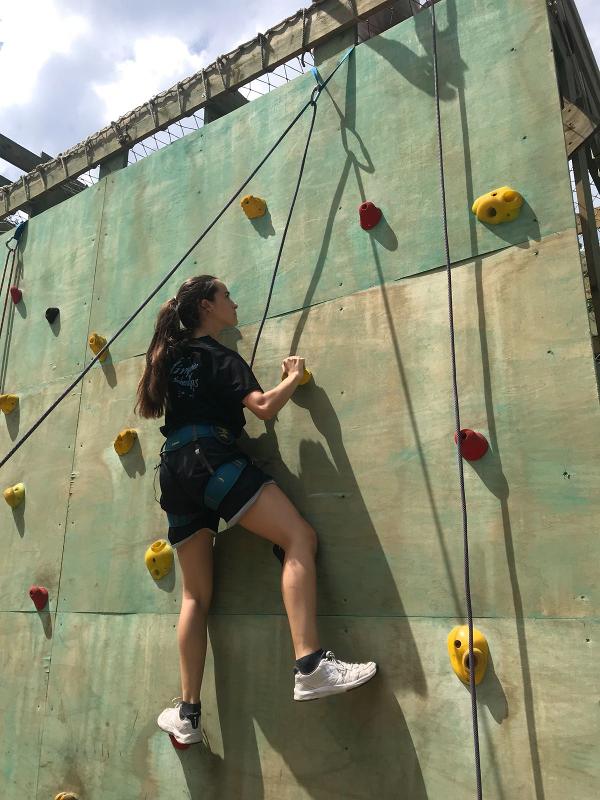 una chica escalando un rocódromo en alquiler instalaciones campamentos