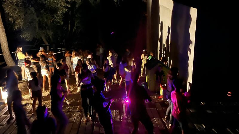un grupo de jovenes bailando por la noche en unos campamentos en ingles españa